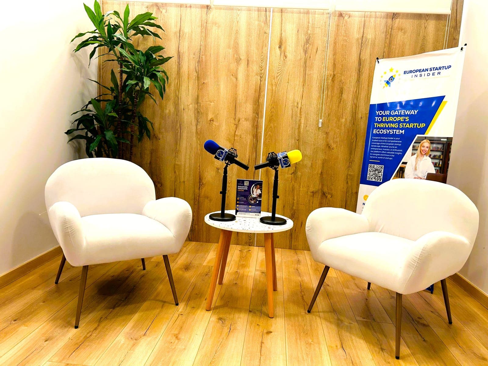 The European Startup Insider interview set: two armchairs either side of a table with branded microphones, a banner behind